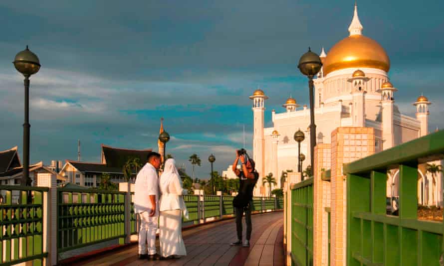 Newlyweds have their picture taken beside the Sultan Omar Ali Saifuddien mosque in Bandar Seri Begawan, a city where gay sex is now punishable by death.