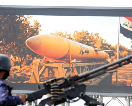 A Houthi soldier mans a machine gun on a pick-up truck in front of a digital billboard