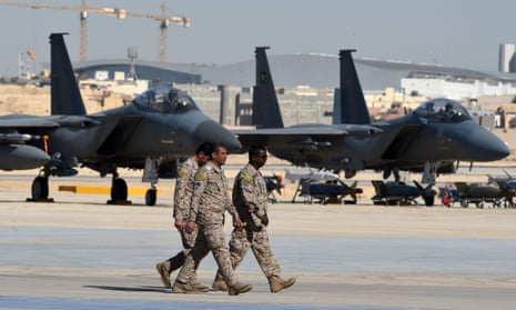 Saudi army officers walk past F-15 fighter jets