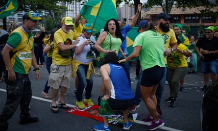 Supporters of Jair Bolsonaro trample on a flag carrying the face of his rival, Lula.