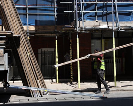 A construction worker carrying scaffold boards