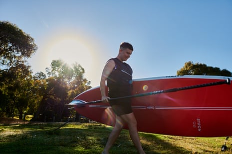 Cait Kelly carries her SUP to the water at Lysterfield Park, near Melbourne