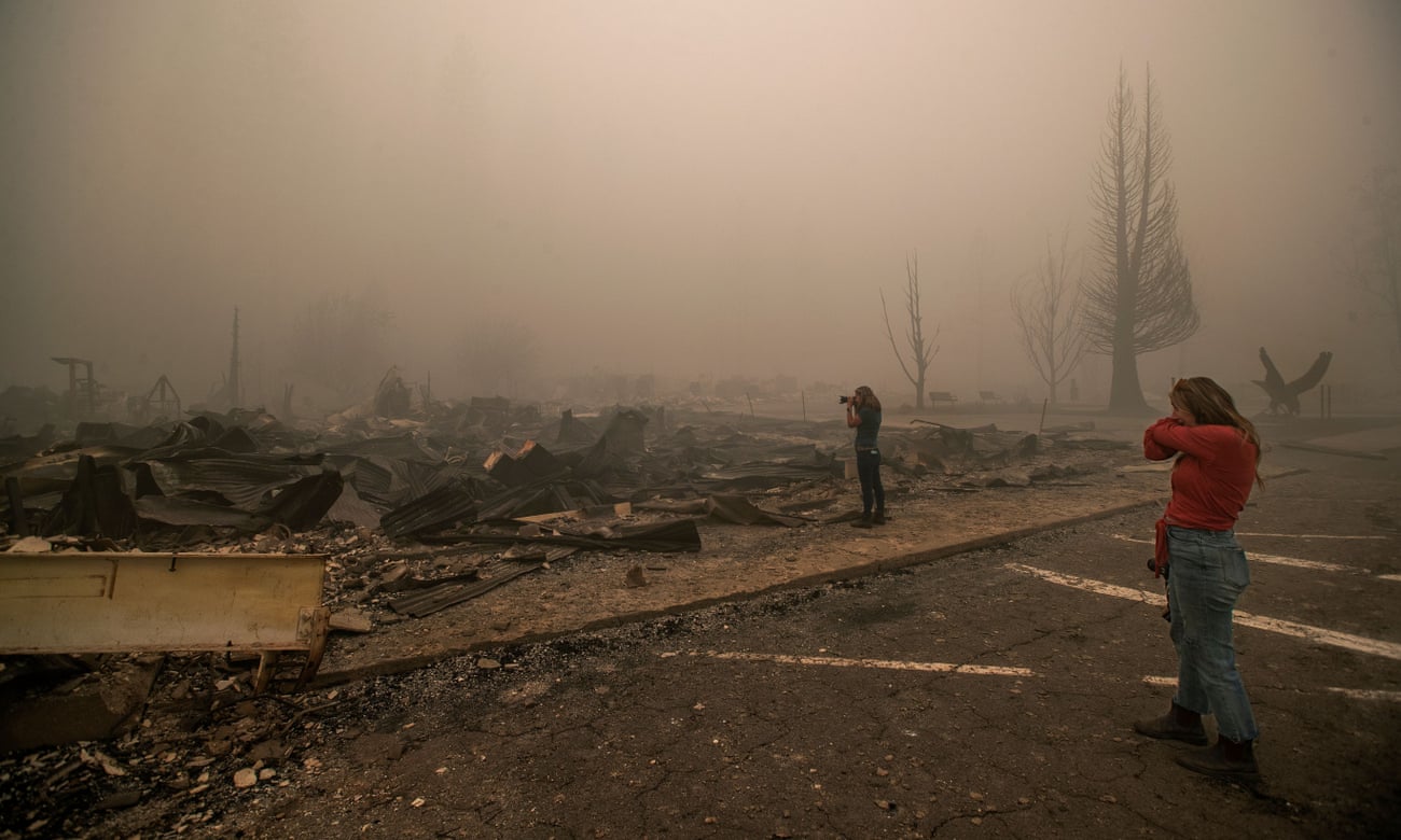 Tiffany Lozano, 44, right, covers her face from the smoke as her sister, Kelly Tan, 59, photographs what is left of Hunter’s Hardware store and the Indian Valley Chamber of Commerce in Greenville.