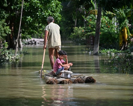 A girl and her grandfather travel on a raft through flood waters in Sivasagar district, 27 July.