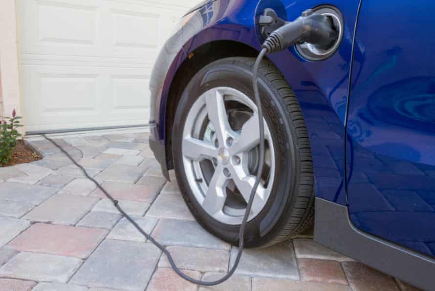 Plug-in hybrid electric car with connector plugged in and charging at home in a driveway