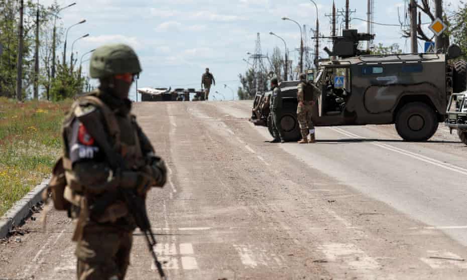 Service members of pro-Russian troops stand guard on a road before the expected evacuation of wounded Ukrainian soldiers from the besieged Azovstal steelworks.