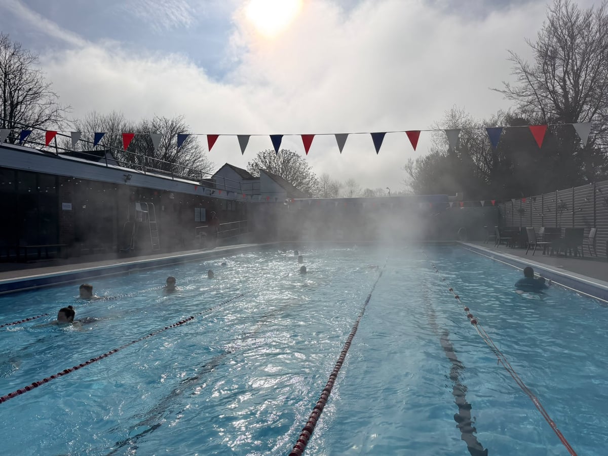 An outdoor pool with steam rising from it on a sunny day