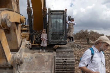 Children play on heavy machinery parked along the roadside as Israelis march between the settlements of Ganim and Kadim on the outskirts of occupied West Bank city of Jenin