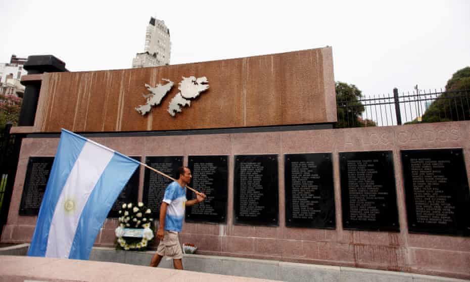 A man carries Argentina’s national flag in front of the wall with names of those who died in the 1982 war between Britain and Argentina in the Falkland Islands.