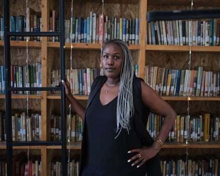 A woman with long braids standing in front of shelves full of books