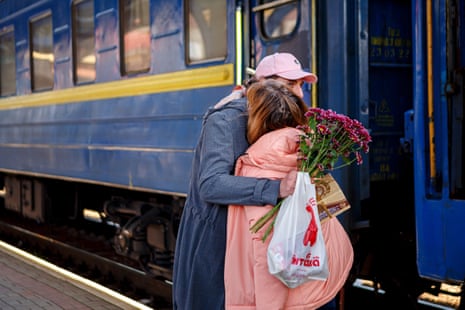 A man with a bouquet of flowers hugs a woman as he meets her at the railway station of Uzhhorod, western Ukraine.