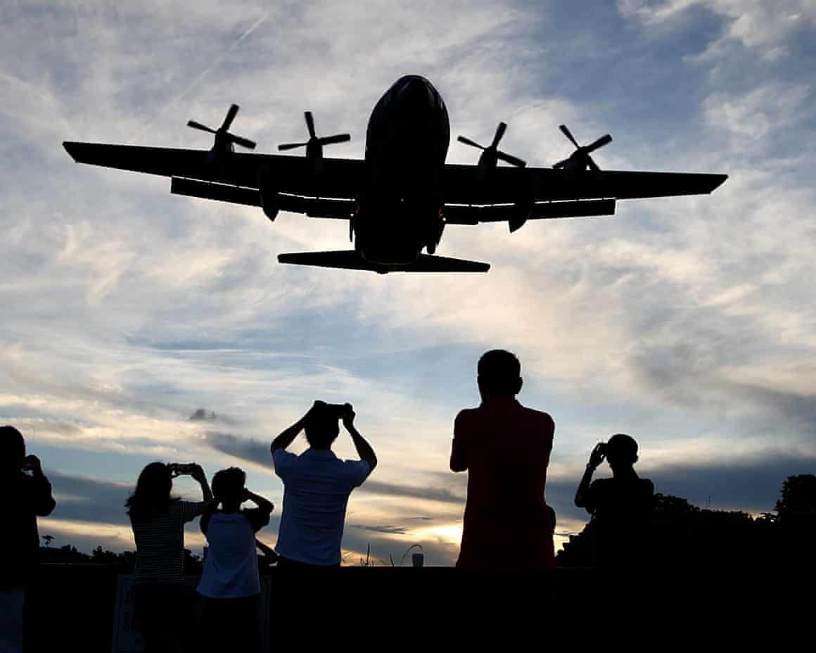 People in Taipei take a photo of a Chinese military plane flying overhead.