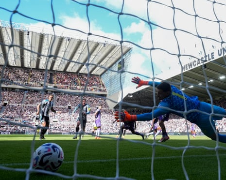 The Bournemouth goalkeeper Djordje Petrovic dives to his left but cannot keep out a shot from Newcastle's Jacob Ramsey.
