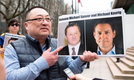 A protester holds photos of Canadians Michael Spavor and Michael Kovrig, who are being detained by China, outside British Columbia supreme court, in Vancouver.