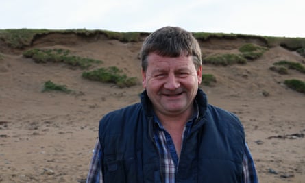 Contractor Martin Kelly stands on the beach inspecting the dunes, where he hopes a wall will be built to prevent erosion and protect the course and low-lying land from flooding.