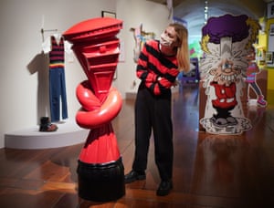London, UK. A staff member poses next to an artwork of a red postbox tied in a knot
