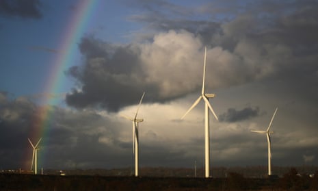 A rainbow appears behind wind turbines