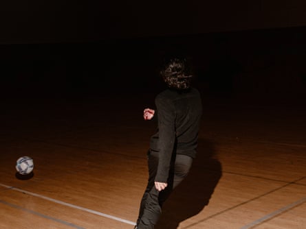 A boy plays football in the dark
