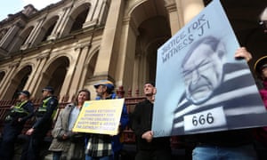 Protesters hold placards outside the court building as Cardinal George Pell is escorted into the supreme court of Victoria in Melbourne