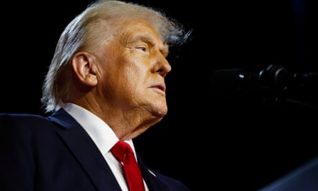 un homme en costume et cravate regarde derrière un microphone