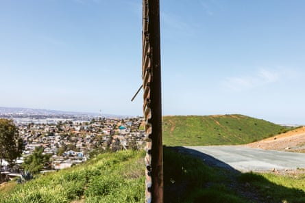 A fence splits the frame in two with a populated valley on the left and open countryside on the right