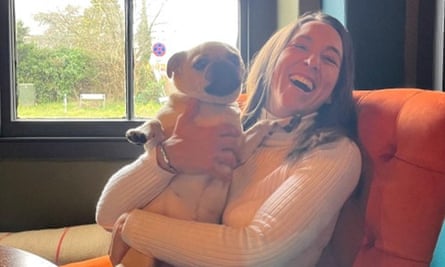 Amie Gray smiling, sitting on a chair and holding a small dog