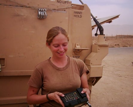 A women smiling near a military vehicle in the desert