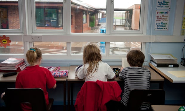 Rear view of three Primary school children sitting at their desk