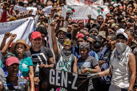 A crowd of people many holding banners or raising a fist in the air.