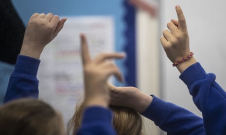Several children's hands in the air with blue sleeves