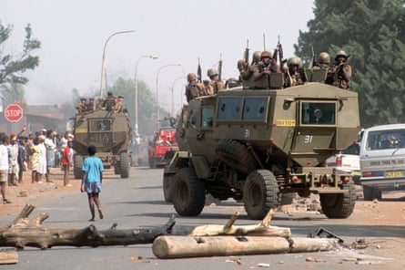 armed soldiers patrol in a military vehicle next to a boy in the street