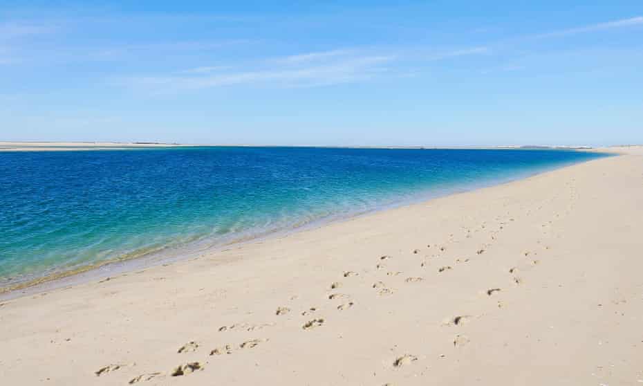 An empty beach in Armona, bathed by a calm sea.