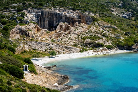 A white beach backed by a landscape of stones and greenery