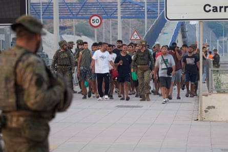 Spanish soldiers escort a group of people across the border into Morocco