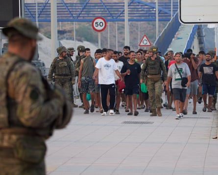 Escorted by the Spanish army, migrants who crossed into Spain return to Morocco from the Spanish enclave of Ceuta