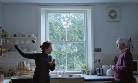 A younger woman and an older man gesticulate in a kitchen.