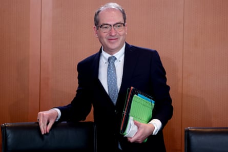 Alexander Dobrindt smiling while holding a folder of papers