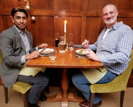 Fraz and Pete sitting at a restaurant table, smiling at the camera