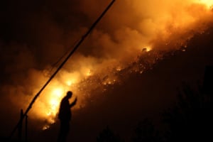 A man is silhouetted against flames of a wildfire