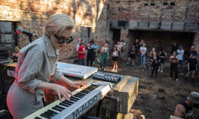 Artist performs while volunteers remove debris from the House of a Culture in the village of Yahidne, Chernihiv.