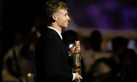 France’s swimmer Léon Marchant carries a lantern with the Olympic flame during the 2024 closing ceremony.