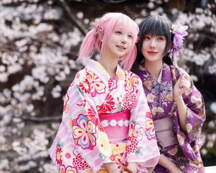 Two young women in kimonos in front of cherry blossoms