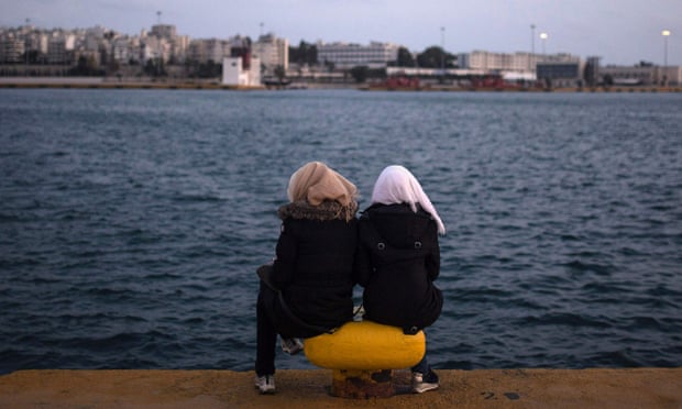 Two women from Syria sit facing the sea at Piraeus harbour in Athens, Greece.