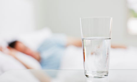 Close-up of glass of water with sick man in background