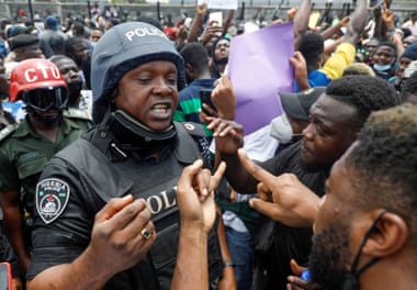 Demonstrators talk to a police officer during a protest over alleged police brutality, in Lagos