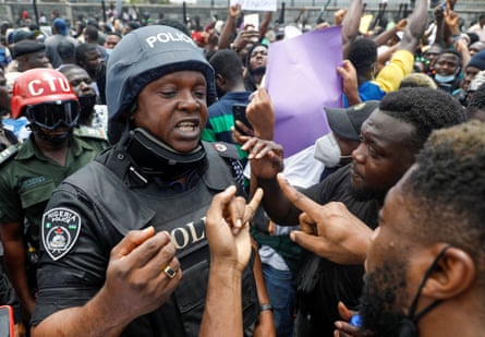 Demonstrators talk to a police officer during a protest over alleged police brutality, in Lagos