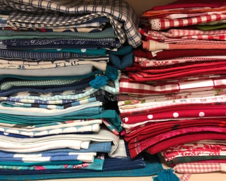Various colourful household fabrics stacked on a shelf in a closet.