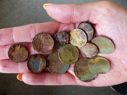 A hand holding a bunch of rusted coins