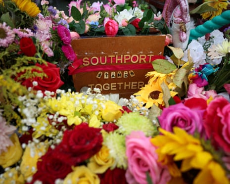 Flowers surround a sign reading 'Southport stands together' in tribute to the victims after the attacks.