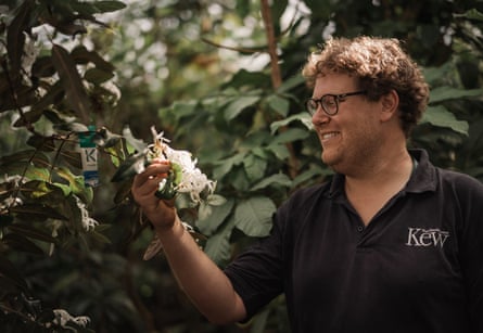 Tom Pickering touching a flowering plant and smiling at it.